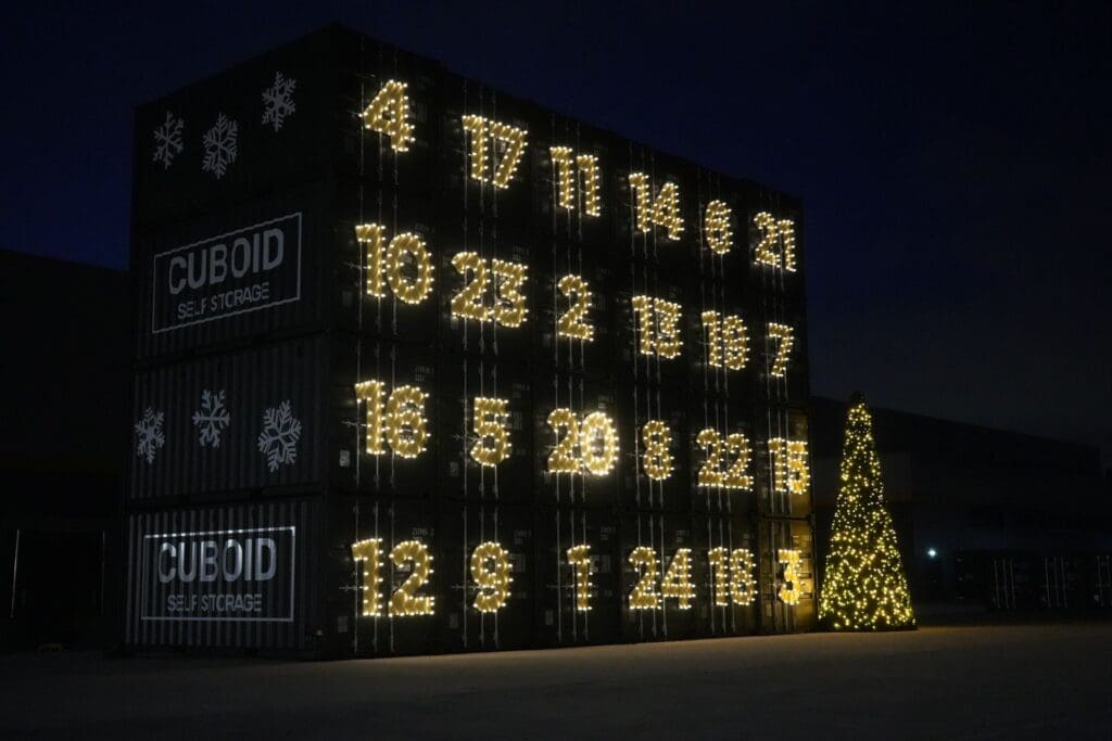 Illuminated Cuboid self-storage containers form a giant advent calendar beside a Christmas tree at night